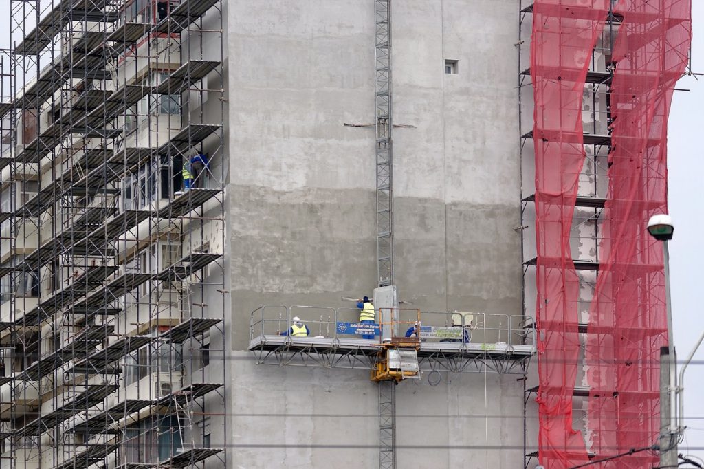 A construction worker diligently constructs a building, wearing safety gear and focused on the task at hand