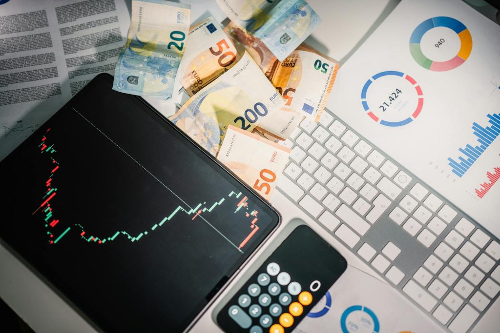 Overhead view of financial tools with Euro banknotes on a desk showing market trends and graphs